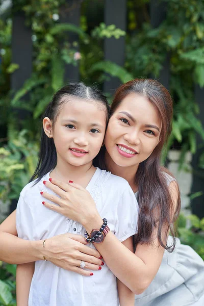 夏の日に屋外で彼女のかわいい小さな娘を抱きしめながら カメラで微笑む若いアジアの母親の肖像画 — ストック写真