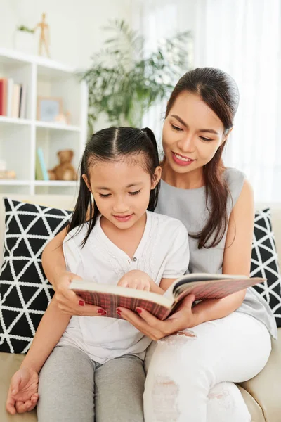 Joven Madre Enseñando Hijita Leer Libro Mientras Sientan Sofá Pasan —  Fotos de Stock