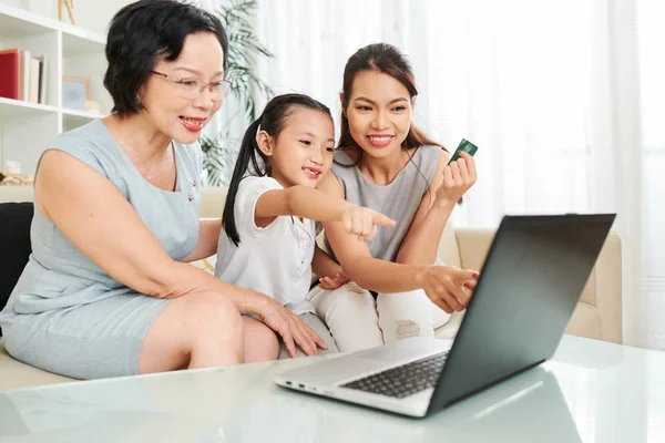 Happy Asian Rodzina Siedzi Kanapie Przed Komputerem Przenośnym Wskazując Idą — Zdjęcie stockowe