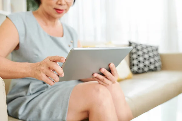 집에서 소파에 앉아있는 디지털 태블릿을 사용하고 온라인으로 통신하는 성숙한 여성의 — 스톡 사진