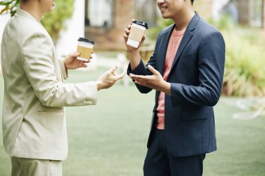 Sokakta duran, kahve içen ve son haberleri ve fikirleri tartışan iki işadamının kırpılmış görüntüsü