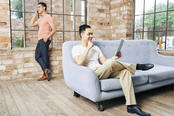 Hombres Negocios Descansando Sofá Leyendo Artículo Tableta —  Fotos de Stock