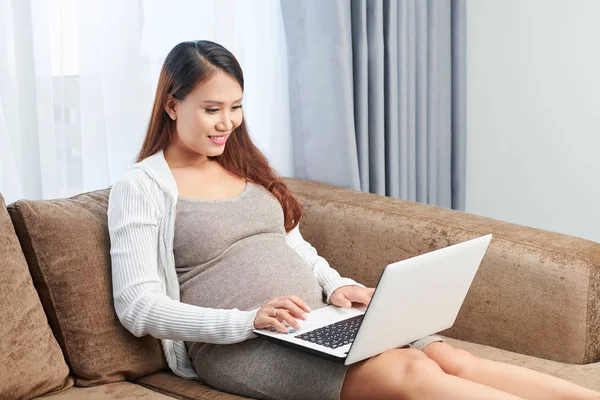 素敵なかわいい若いアジアの妊娠中のビジネスウーマンは 自宅でソファに座って メールに答えます — ストック写真