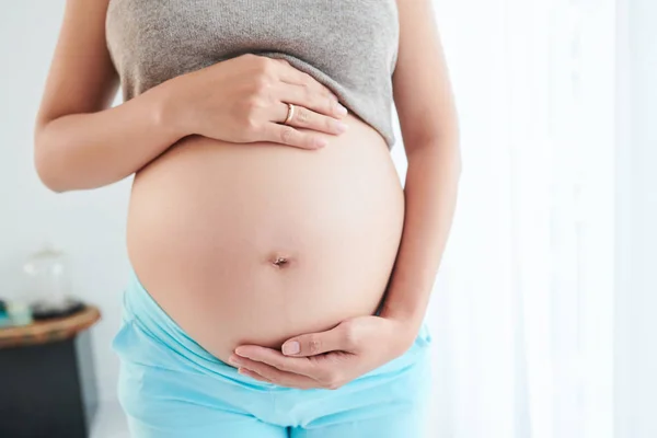赤ちゃんを予想するときに彼女の大きな妊娠中の腹を示す女性のトリミング画像 — ストック写真
