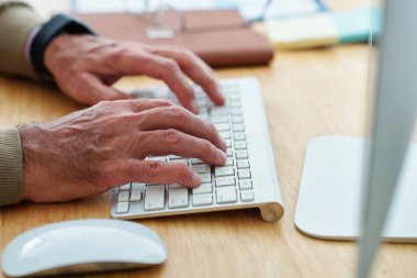 Ofis masasında bilgisayar başında çalışırken klavyede yazan kıdemli işadamı veya yazılım mühendisinin elleri