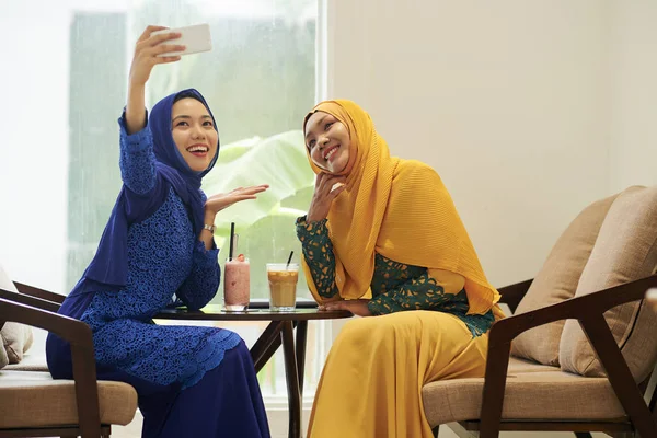 Hijabs mutlu genç Asyalı kadınlar ve kafede fotoğraf geleneksel elbiseler