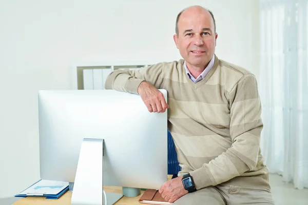开朗的中年商人坐在办公桌边上 靠在电脑屏幕上的肖像 — 图库照片