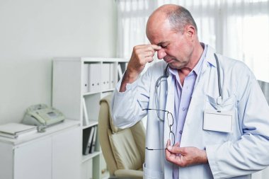 Deneyimli Kafkas doktor gözlük kapalı alarak ve burun köprüsü masaj migren muzdarip