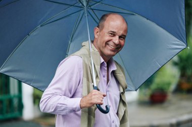 Yağmurlu bir günde büyük şemsiye ile açık havada yürüme keyfini olumlu olgun adam Portre