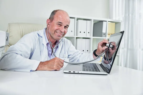 Smějící Středně Zestárlý Praktický Lékař Naslouchající Obrazovce Přenosného Počítače Stetoskskopem — Stock fotografie