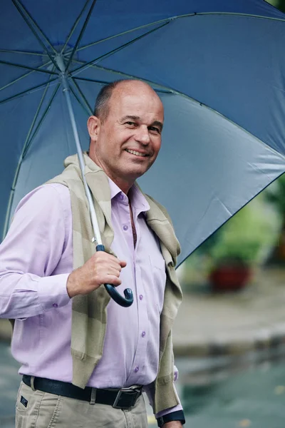 快乐成熟的男人在雨中拿着大伞走在大街上 — 图库照片