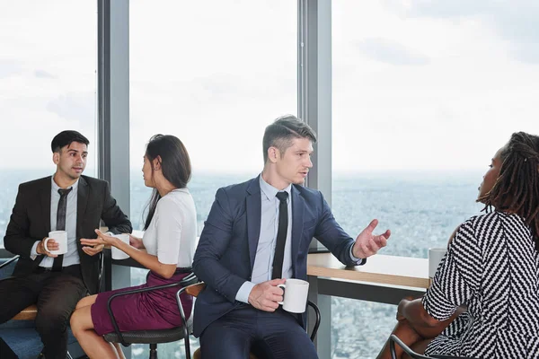 Business people sitting at wooden counter at panoramic window, drinking coffee and discussing various news and idea