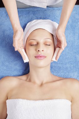 Tedavigençleştirmeden önce hastanın yüzünü temizlerken pamuk ped kullanan kozmetolojist