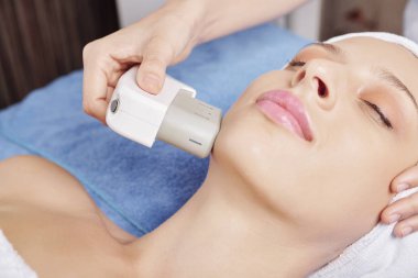 Güzel genç kadın spa salonunda profesyonel ultrason yüz tedavisi oluyor