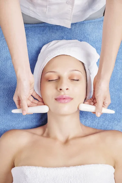 Cosmetologo Utilizzando Bastoni Pietra Quando Massaggiare Viso Rilassante Giovane Donna — Foto Stock
