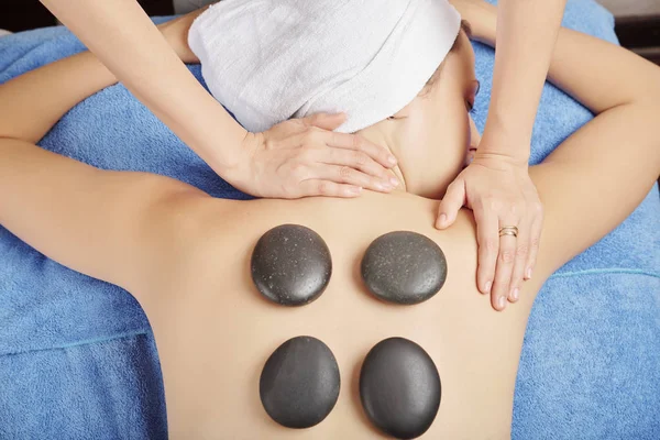 Masajista Poniendo Piedras Calientes Basalto Espalda Joven Masajeando Cuello Hombros —  Fotos de Stock