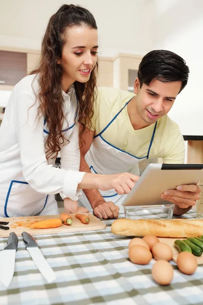 Lächelndes Junges Paar Steht Küchentisch Und Sucht Online Nach Guten — Stockfoto