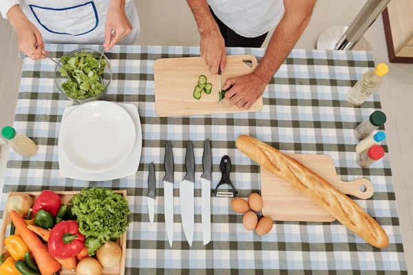 Mãos Mulher Misturando Salada Quando Seu Namorado Cortando Pepino Mesa — Fotografia de Stock