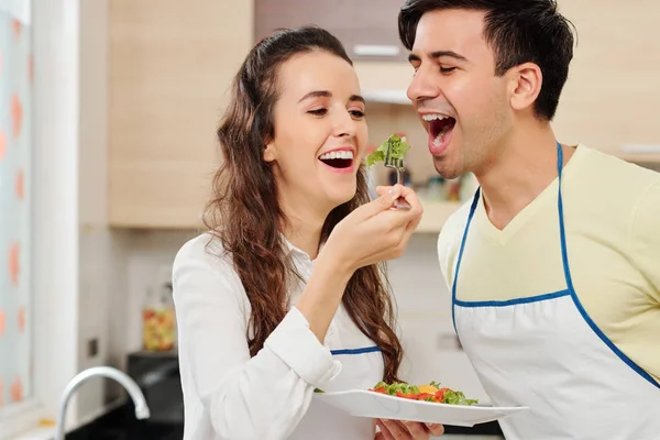 かなり若い女性は 彼女が夕食のために作った健康的なサラダを味わうために夫を求める — ストック写真