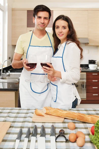 Joven Pareja Caucásica Delantales Pie Mesa Cocina Con Copas Vino —  Fotos de Stock