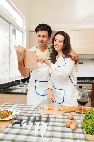 Positivo Jovem Casal Caucasiano Aventais Receita Leitura Livro Culinária Fazer — Fotografia de Stock