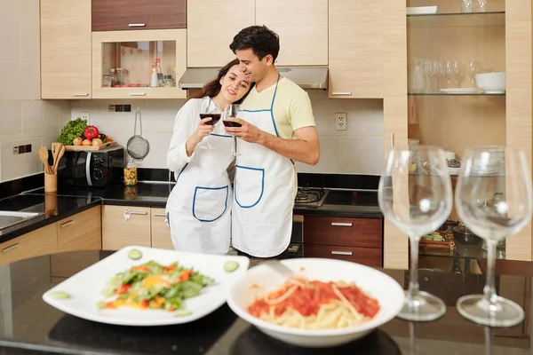 疲れたが幸せな若いカップルは 自宅で夕食を調理した後 赤ワインを飲みます — ストック写真