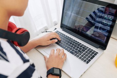 Dizüstü bilgisayarda akıllı saat ve kulaklık programlama ile Genç çocuk, o yarattığı yeni yazılım test ediyor