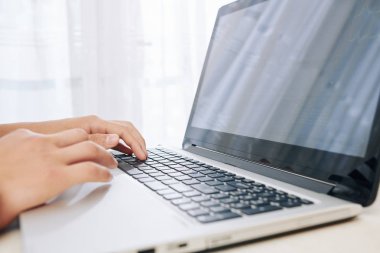 Dizüstü bilgisayar üzerinden internet üzerinden okul için bilgi arayan genç çocuk Eller