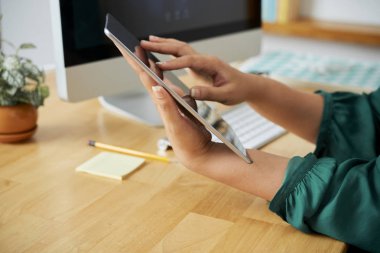 İşyerinde oturan ve ofiste online mektup yazan dijital tabletin ekranına dokunan iş kadınının yakın çekimi