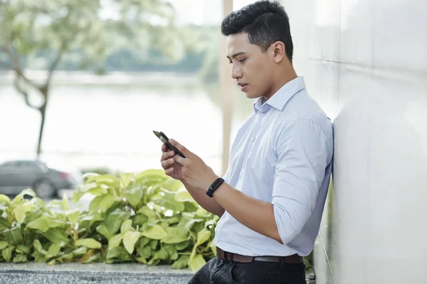 Serious Young Vietnamese Entrepreneur Standing Outdoors Checking Notifications Smartphone — Stock Photo, Image