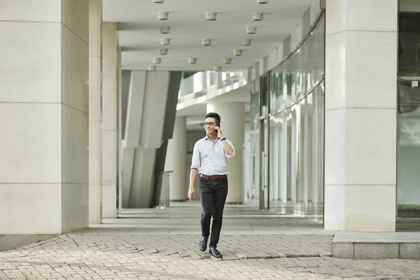 Позитивный Молодой Азиатский Предприниматель Очках Оглядывается Разговаривает Телефону Ходьбе Улице — стоковое фото