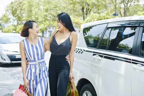 两个兴奋的亚洲妇女带着购物袋拥抱在一起 在城市见面时大笑 — 图库照片