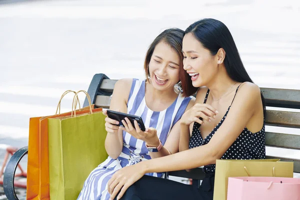 Aziatische Jonge Vrienden Zittend Bankje Samen Met Boodschappentassen Kijken Mobiele — Stockfoto