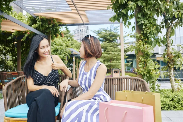 Alışveriş Poşetleri Ile Iki Asyalı Arkadaş Kanepede Oturan Birbirleriyle Konuşurken — Stok fotoğraf