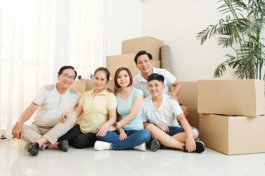 Neşeli büyük Vietnamlı aile içinde eşyalarını ile karton kutular büyük yığını önünde oturan