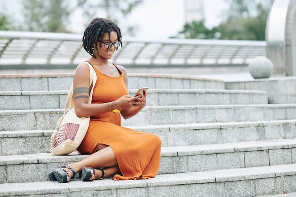 Африканская Красивая Женщина Сидящая Лестнице Печатая Сообщение Мобильном Телефоне Улыбаясь — стоковое фото