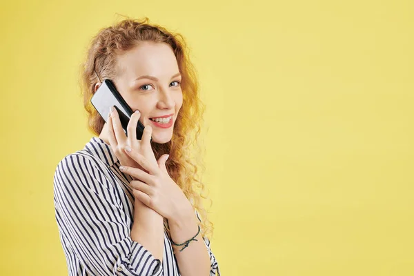 Retrato Jovem Encaracolado Feliz Camisa Listrada Falando Telefone Isolado Amarelo — Fotografia de Stock