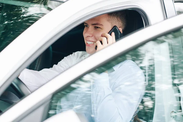 Giovane Uomo Che Parla Sul Cellulare Sorride Mentre Siede Volante — Foto Stock