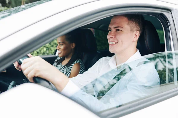 Mladý Usměvavý Muž Drží Volant Řídí Auto Vedle Kterého Sedí — Stock fotografie