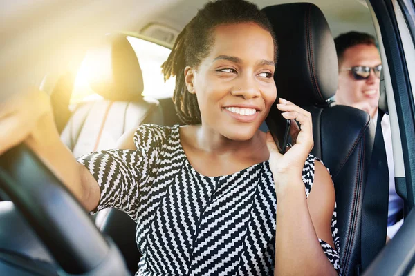 車を運転しながら携帯電話で話している車の後ろに座っているアフリカの若い女性と笑顔後部座席で車を運転しながら — ストック写真