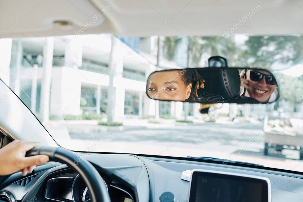Close-up of reflection of woman and man in the rearview mirror while they travelling by car