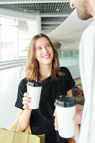 Beautiful young Caucasian woman drinking take out coffee with boyfriend after shopping in mall together on Saturday