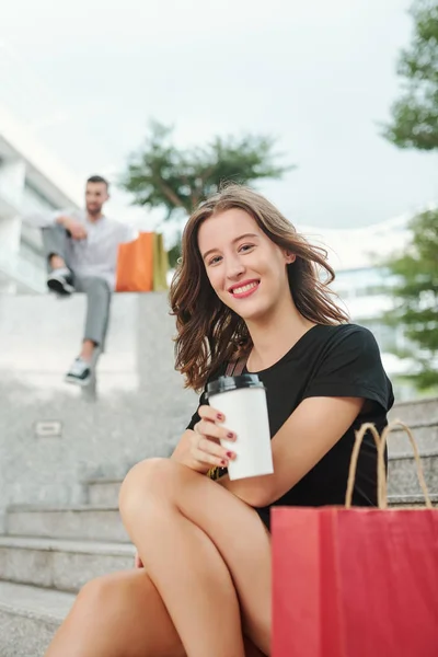 白种人可爱而快乐的年轻女子在购物了一整天后 躺在台阶上 端着一杯咖啡离去的画像 — 图库照片
