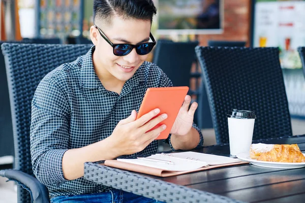 カフェテーブルに座って 朝食やニュースをオンラインで読む正の若い男の肖像画 — ストック写真