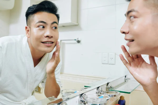 Bonito Positivo Jovem Asiático Homem Aplicando Hidratante Loção Rosto Frente — Fotografia de Stock