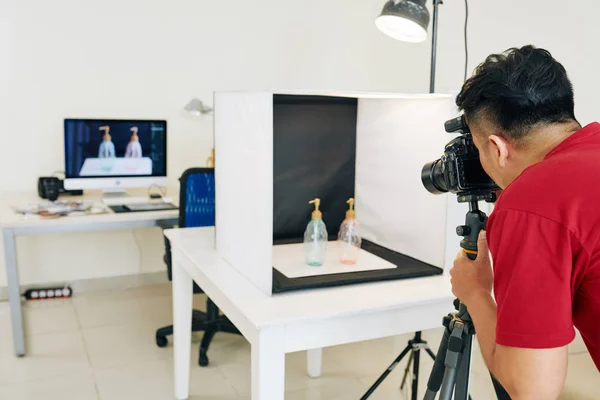 摄影师在小工作室用黑色背景的浅立方体拍摄玻璃瓶的照片 — 图库照片