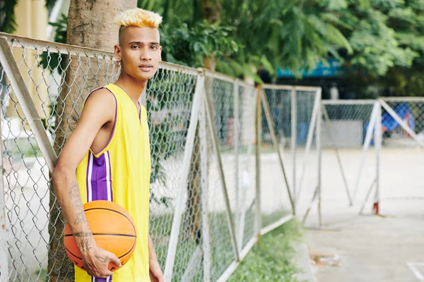 Yakışıklı Genç Oyuncu Sokak Basketbol Sahasında Metal Ağa Yaslanmış Kameraya — Stok fotoğraf
