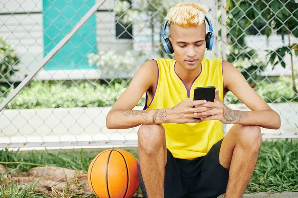 Junger Gutaussehender Mann Sitzt Auf Einem Street Basketballplatz Und Hört — Stockfoto