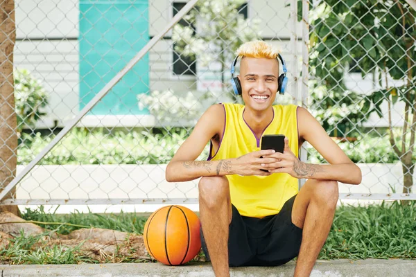 Porträtt Glada Skrattar Ung Svart Basketspelare Sitter Utomhus Med Smartphone — Stockfoto