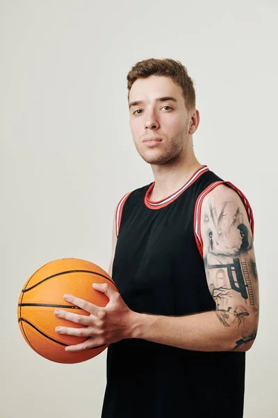 カメラを見て手でボールと本格的な自信のプロバスケットボール選手の肖像 — ストック写真
